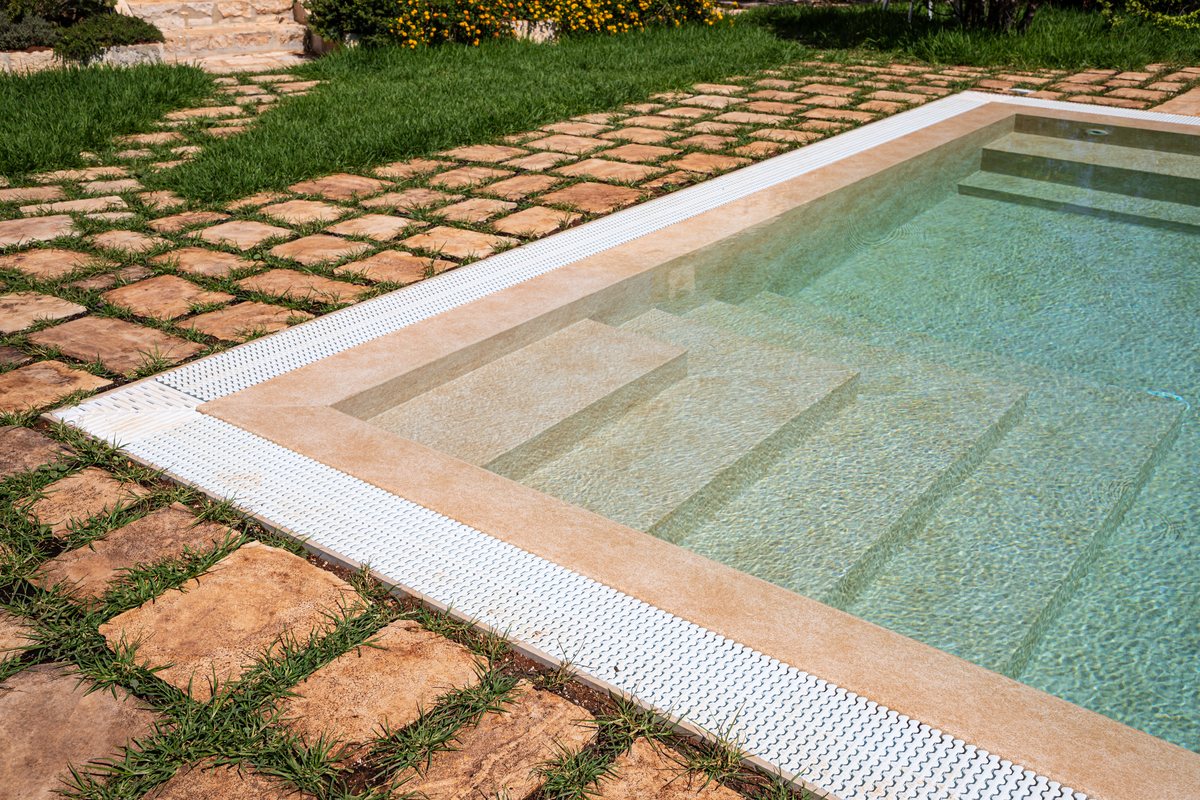 Bordo di una piscina con pavimentazione in pietra e canalina di scarico